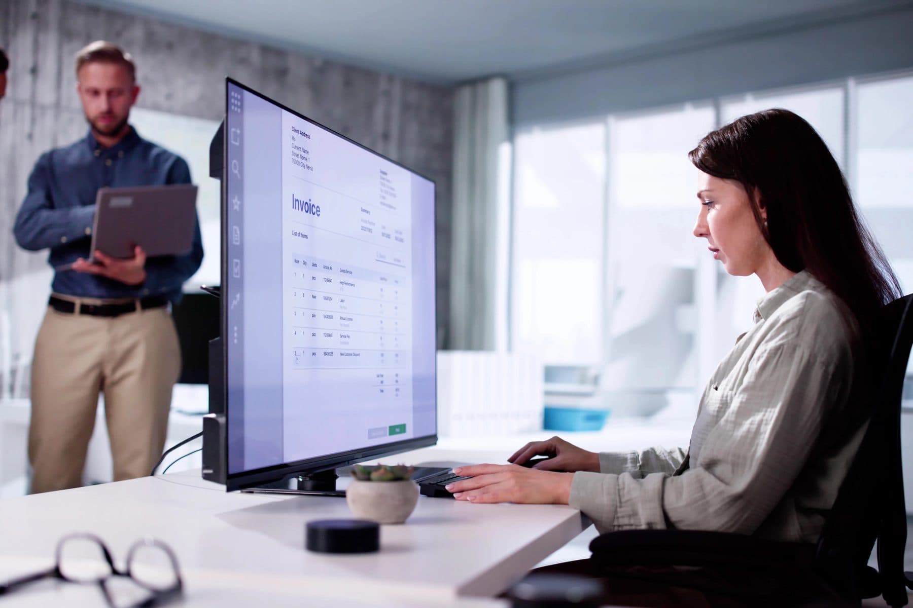 A professional working at a desk with a large monitor in a modern office