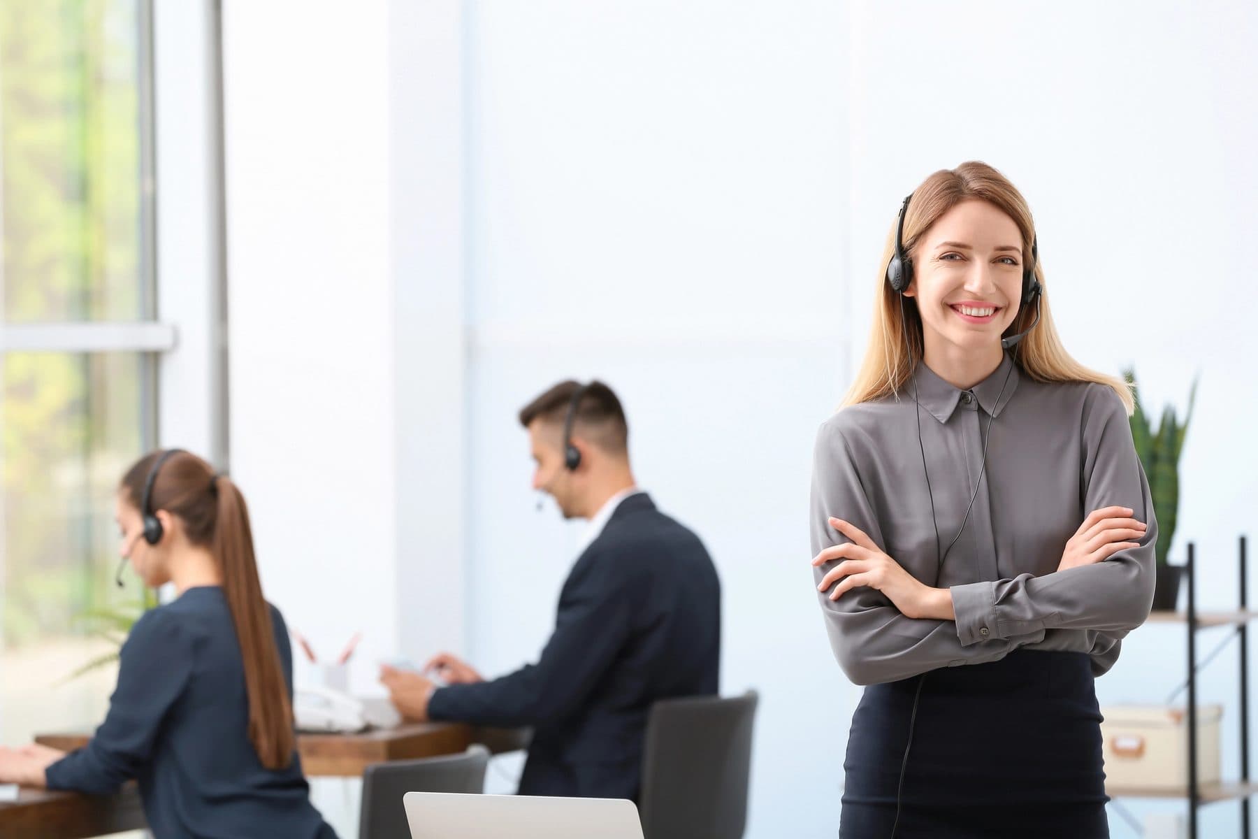 A professional wearing a headset in a bright office with colleagues behind