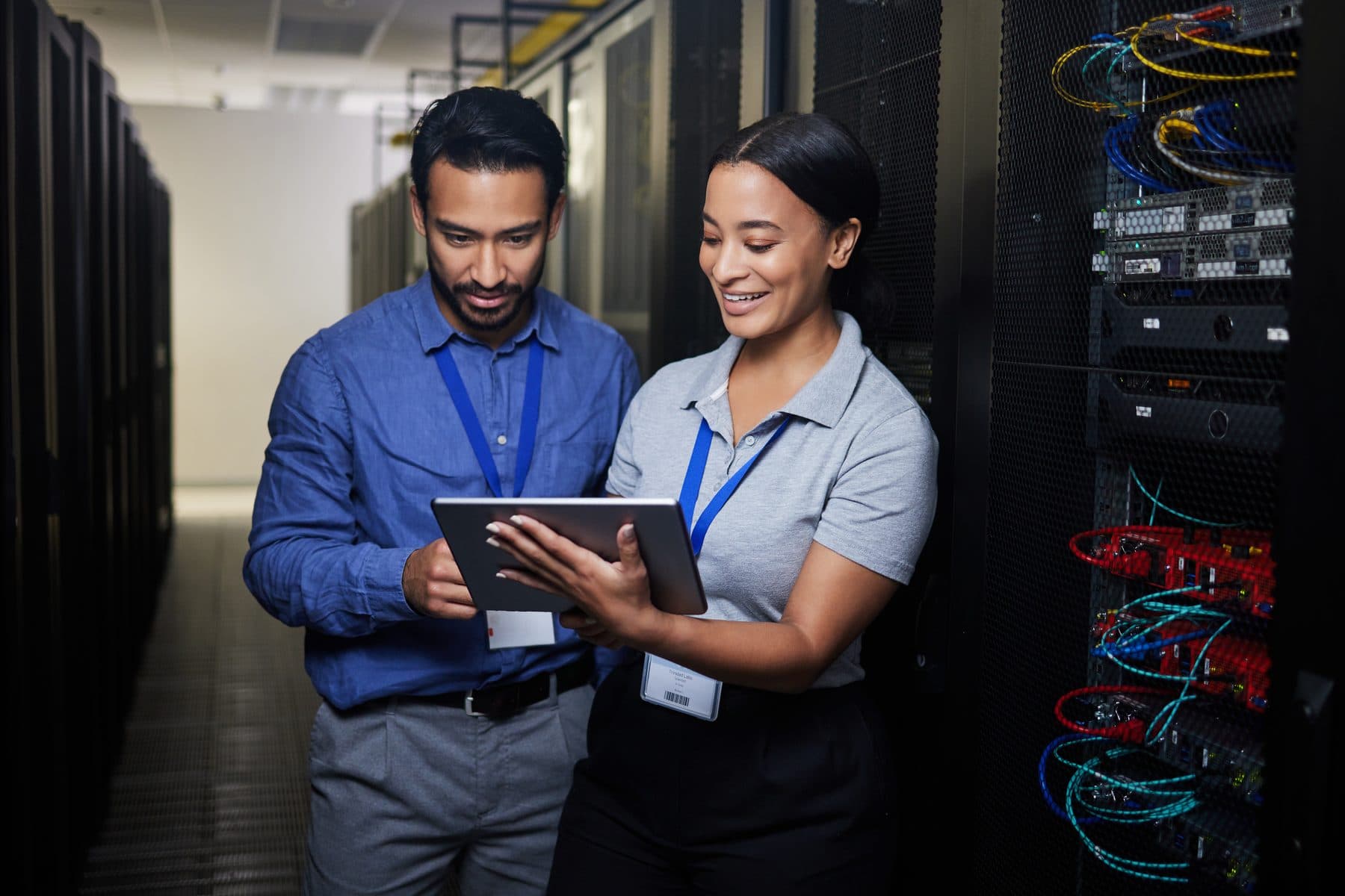 Two technicians reviewing a tablet in a server room