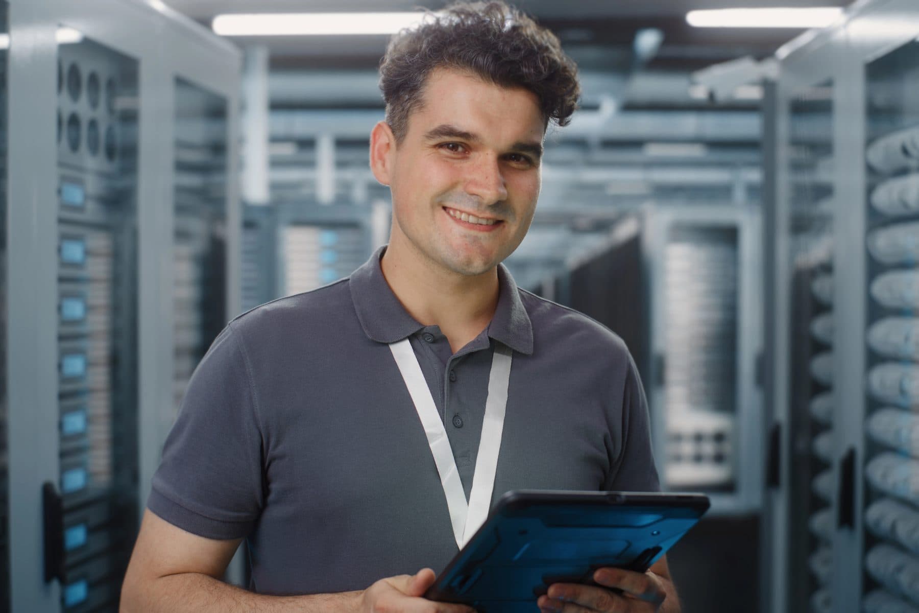 A smiling technician in front of a neatly cabled network rack
