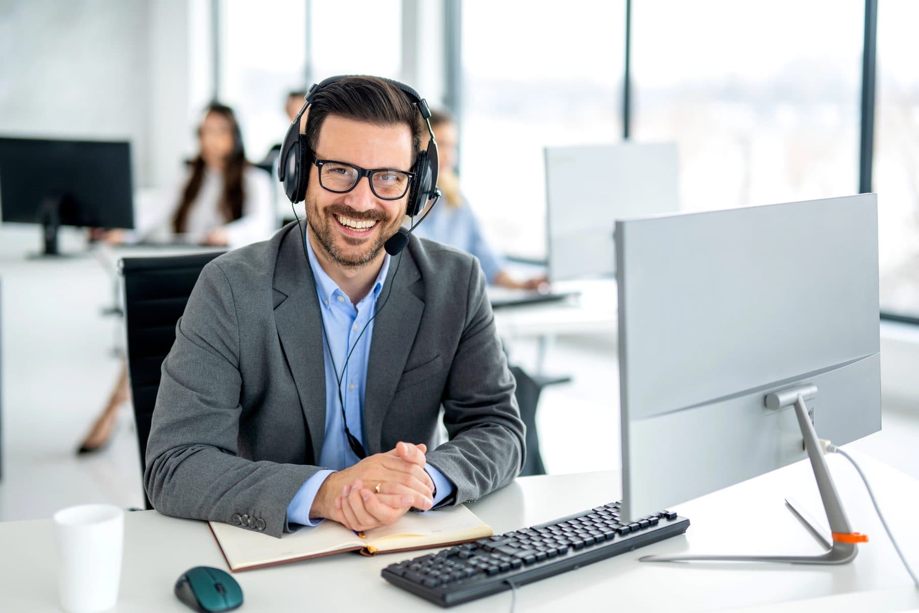 A help desk technician wearing a headset in a bright office
